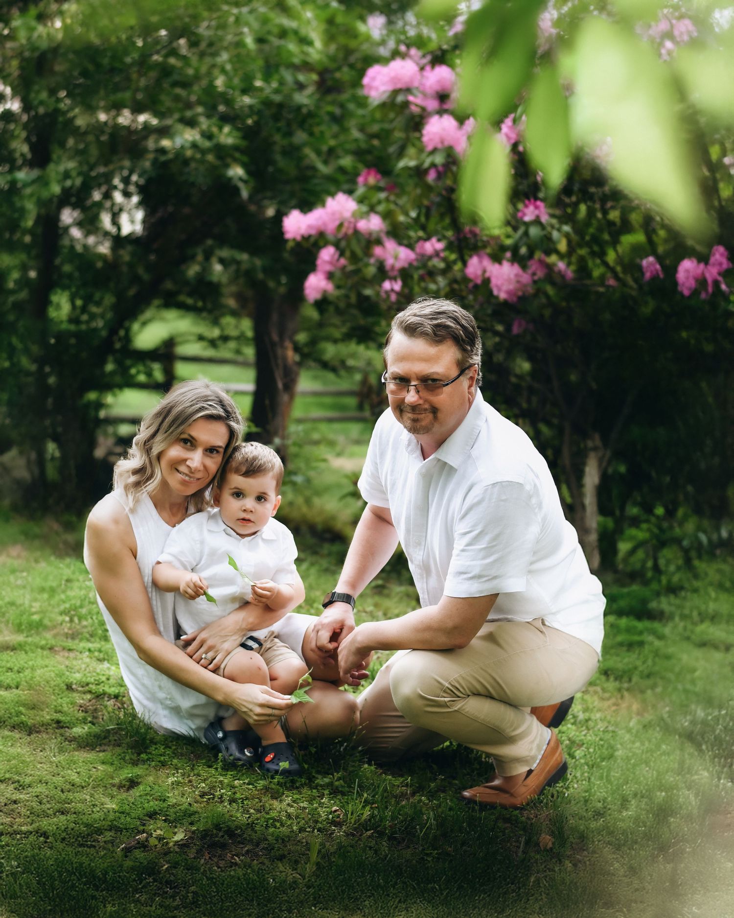 Family enjoying a sunny day together under blooming pink trees in a park setting.