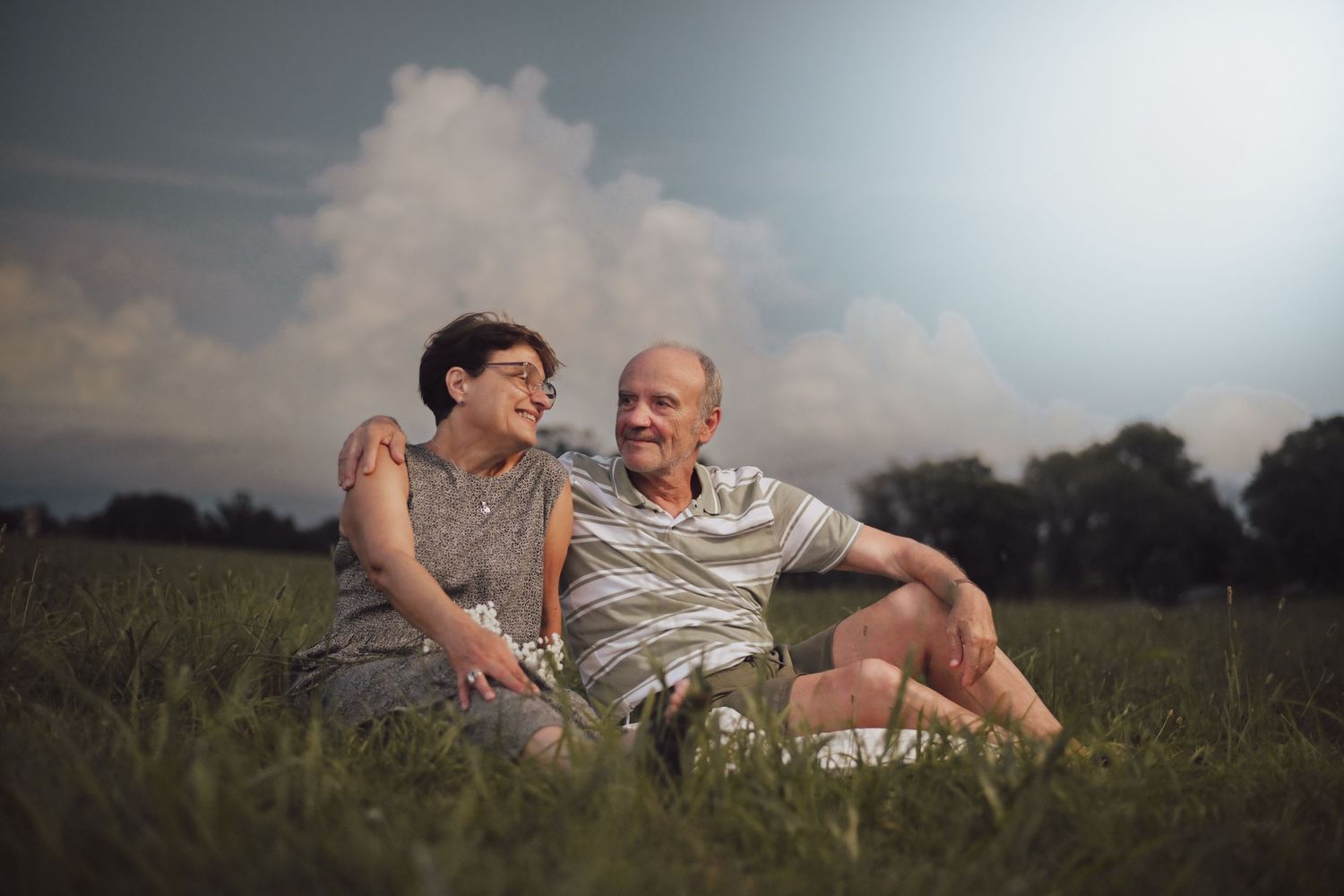 Couple relaxing together in a meadow during golden hour.