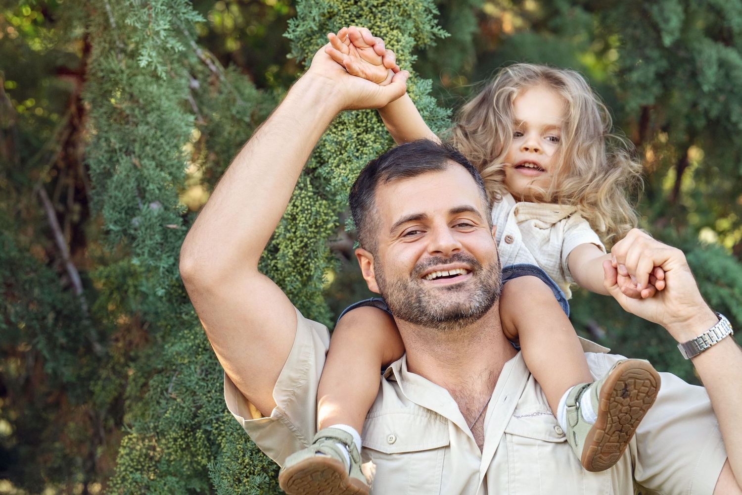 Happy father carrying smiling child during their family portrait session near the Main Line, PA.