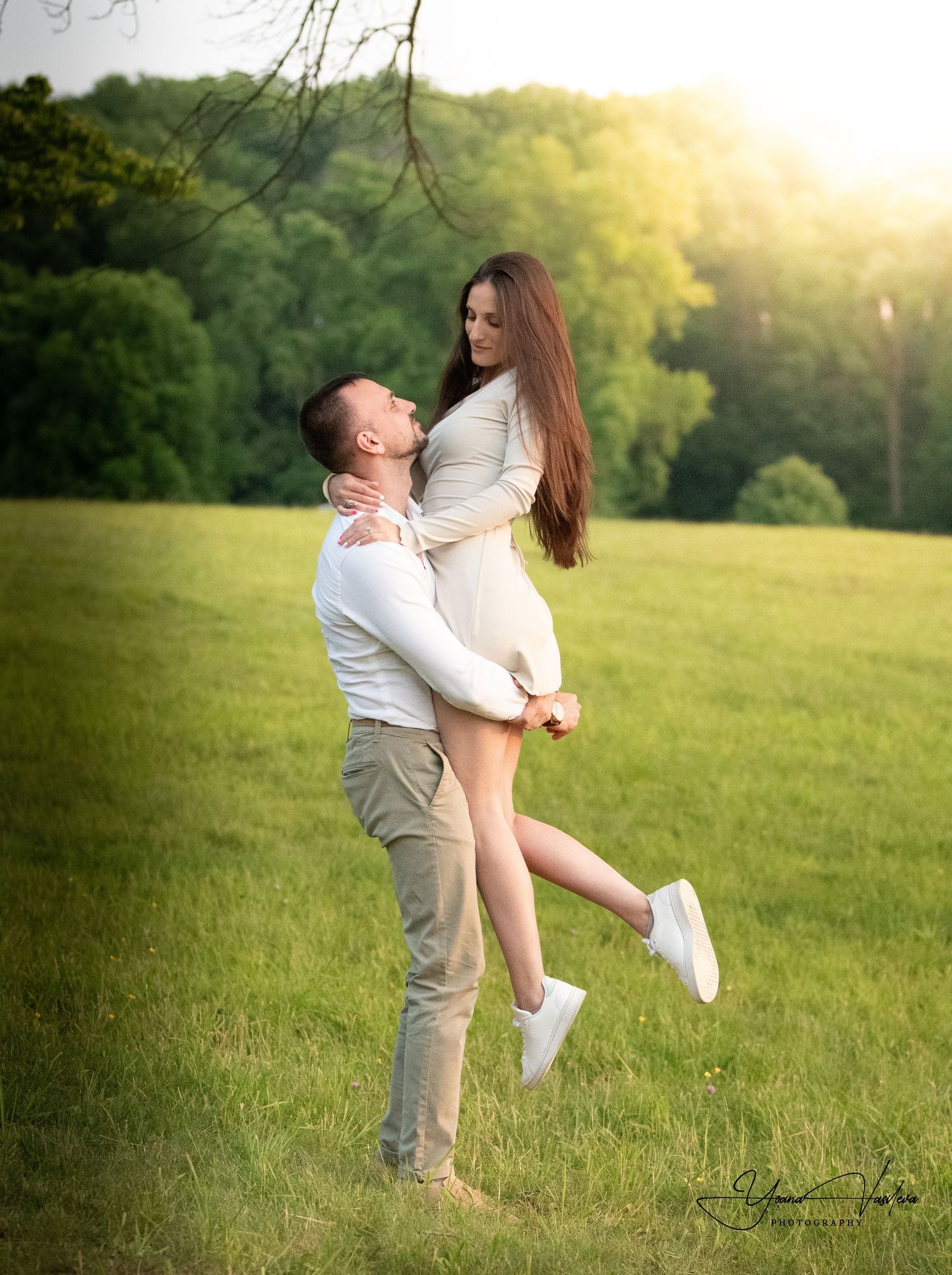 Romantic couple embracing in a sunlit meadow during golden hour.