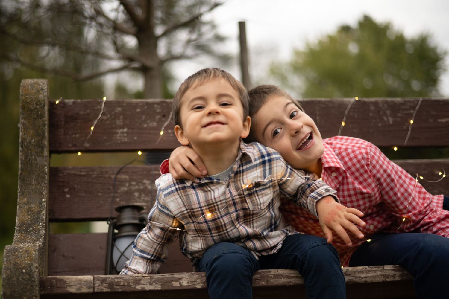 Children laughing together while sitting on a wooden park bench.