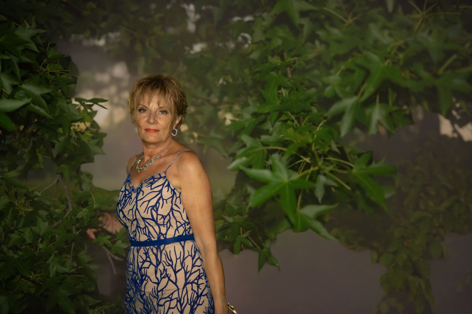 Evening outdoor portrait with floral patterned dress against natural foliage.
