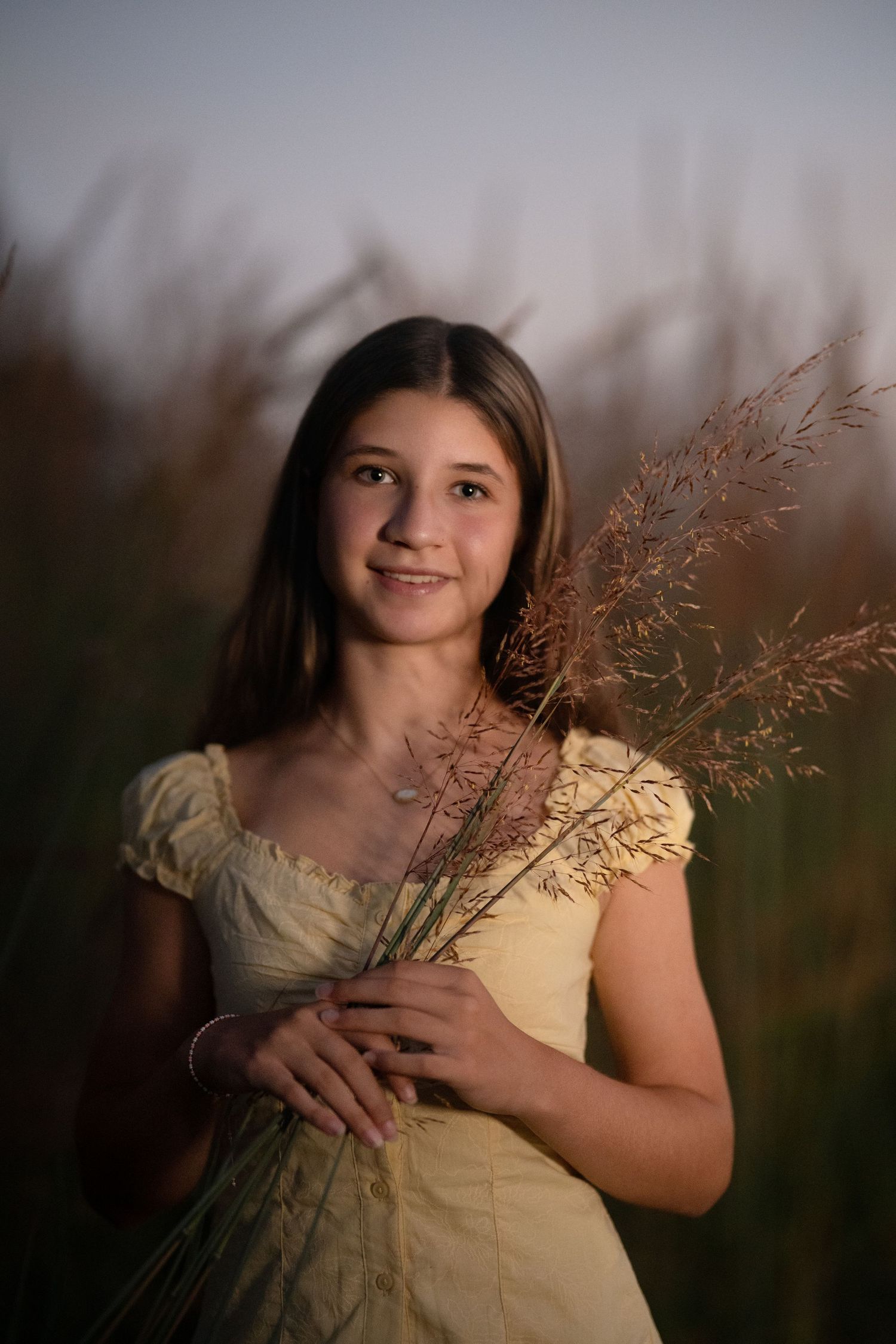 High school senior holding wildflowers during a golden hour portrait session on the Main Line, PA.