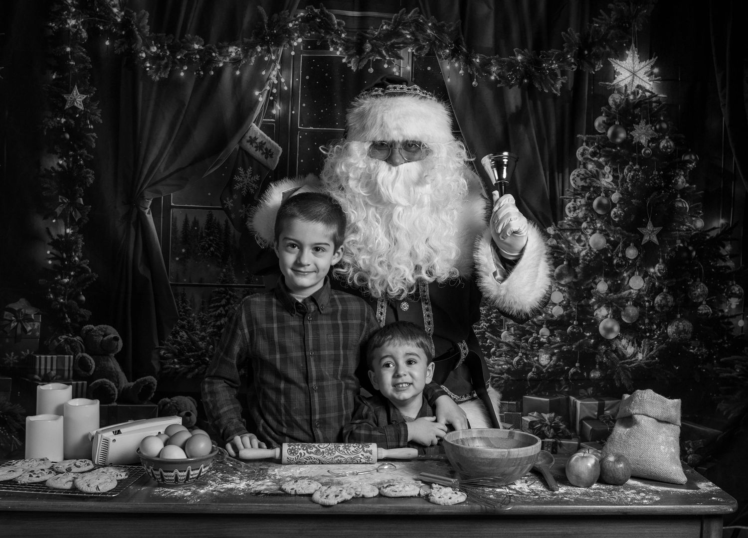 Black and white Christmas scene showing holiday baking and decorations on rustic table.