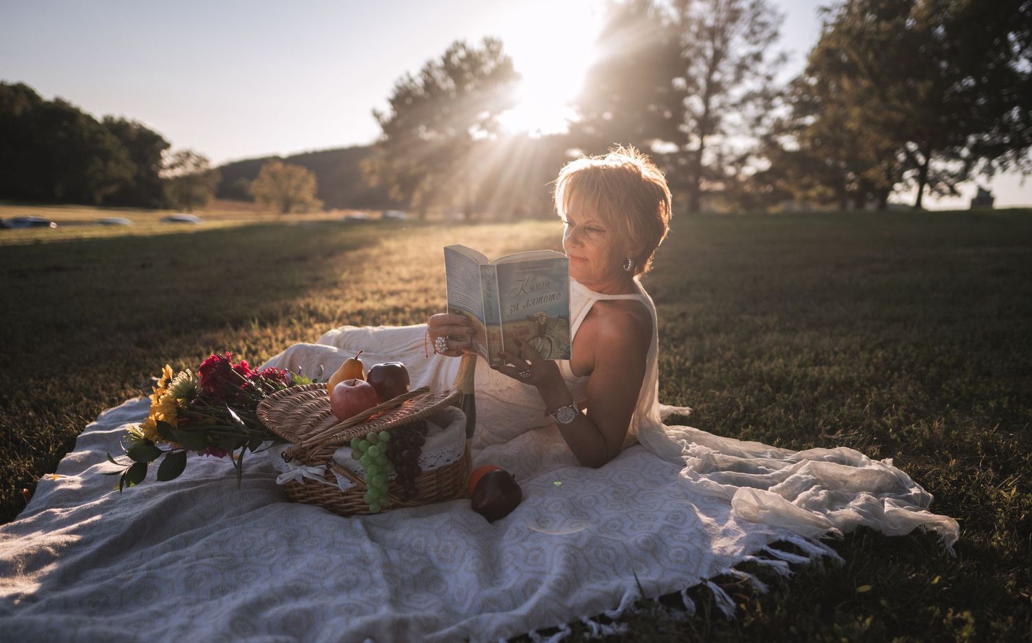 A sunset picnic scene with a blanket spread on grass and glowing golden light.