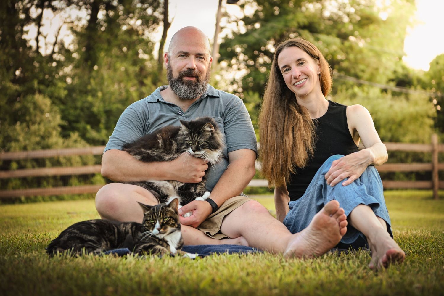 Family relaxing outdoors with their cat during a golden sunset photo session.