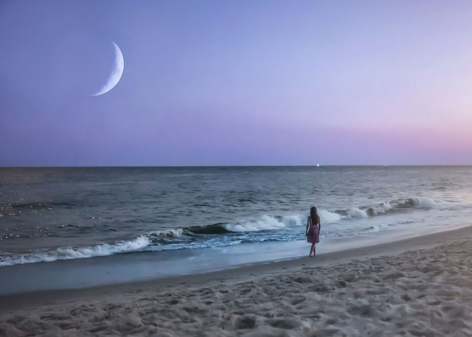 Scenic beach landscape at sunset with crashing waves and a crescent moon in the purple sky.