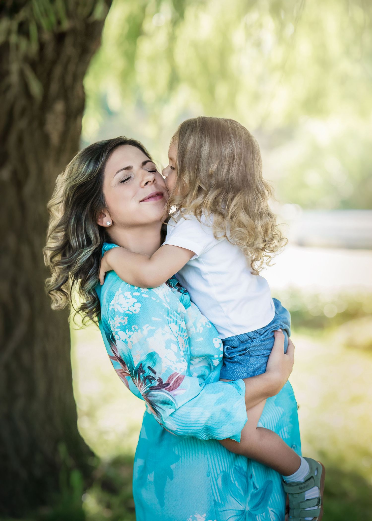 A mother holds her young curly-haired child at golden hour during their Mommy & Me portrait session on the Main Line, PA.