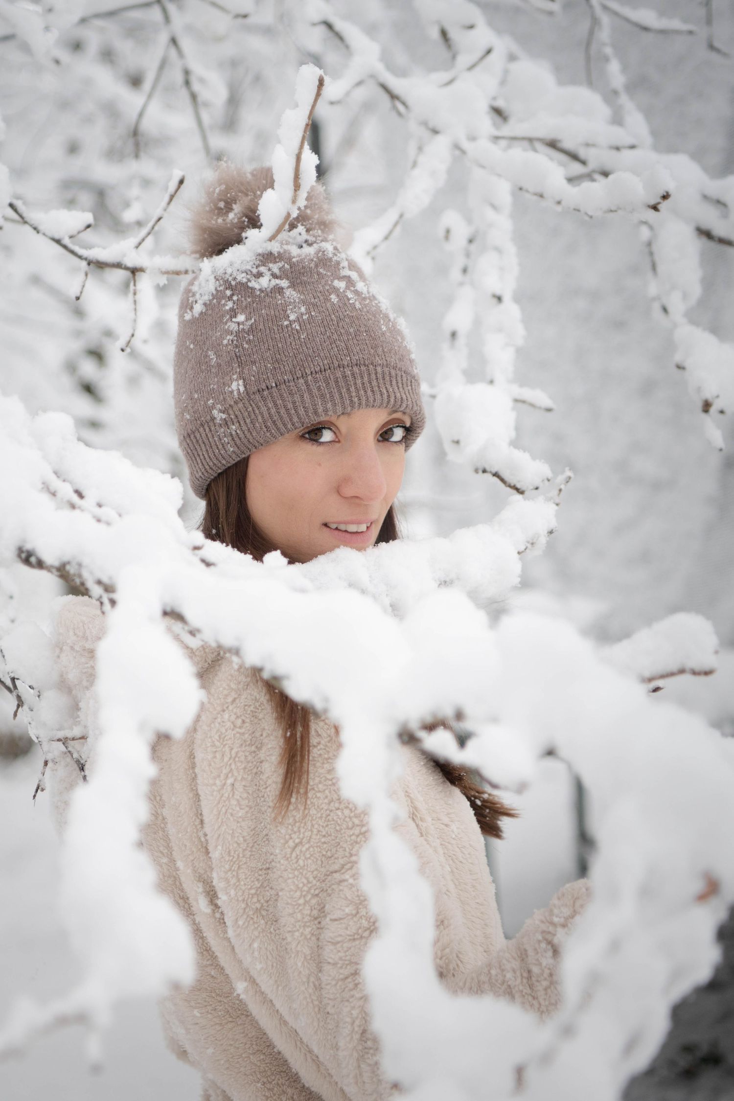 Winter portrait with snow covered branches and warm knit accessories.