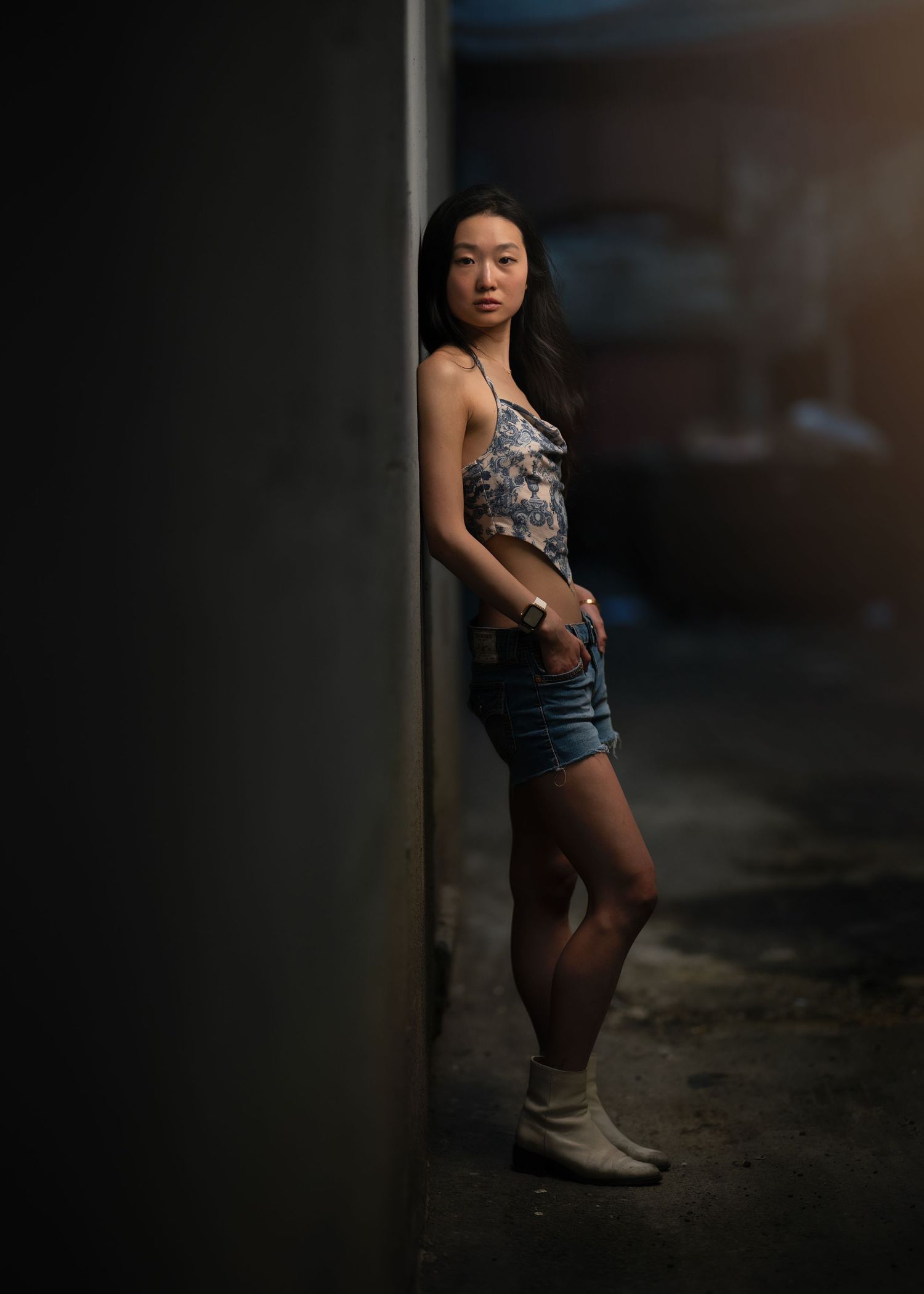 A high school senior posing elegantly in a back alley during her lifestyle senior session near the Main Line, PA.