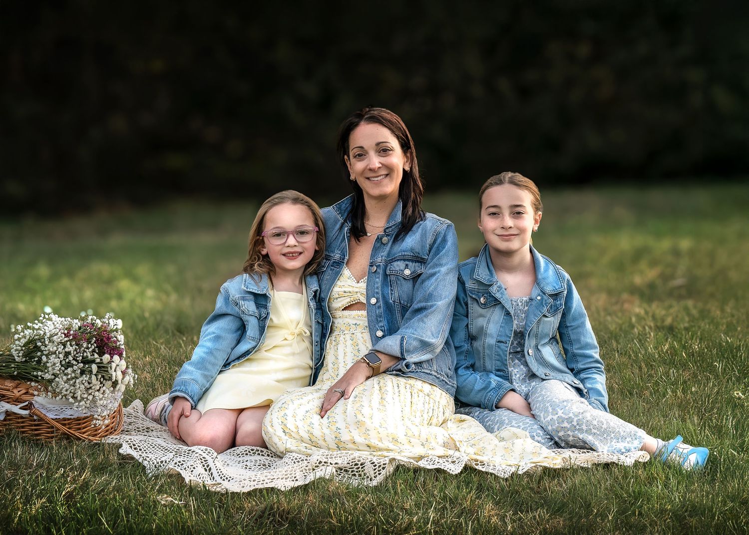 A woman and two young girls in denim jackets sit smiling during their Mommy & Me portrait session on the Main Line, PA.