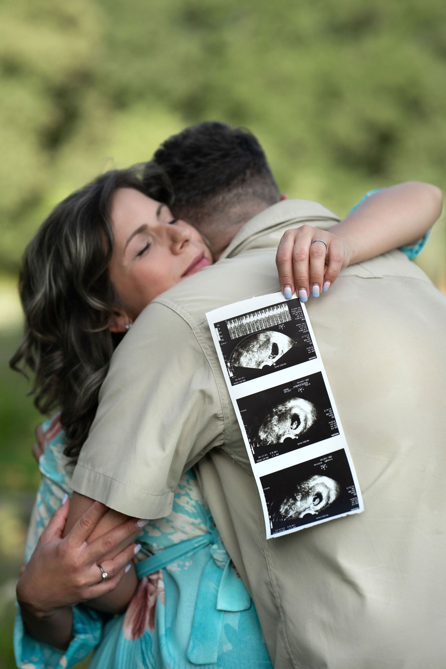Couple holding ultrasound photos during their outdoor pregnancy announcement photography session near Wayne, PA.