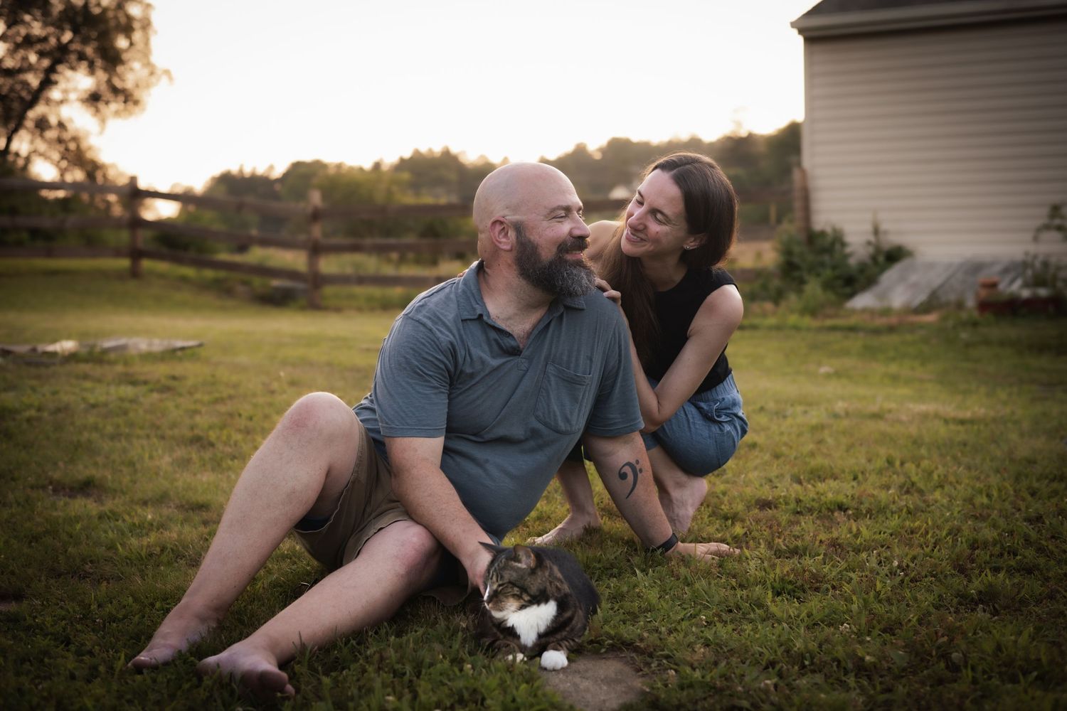 Couple shares intimate moments while relaxing on grass during sunset.