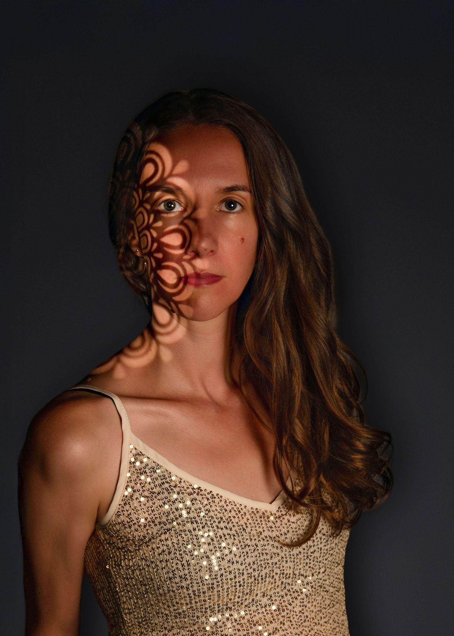 Woman posing against a dark backdrop during her women's glam studio photo session on the Main Line, PA.