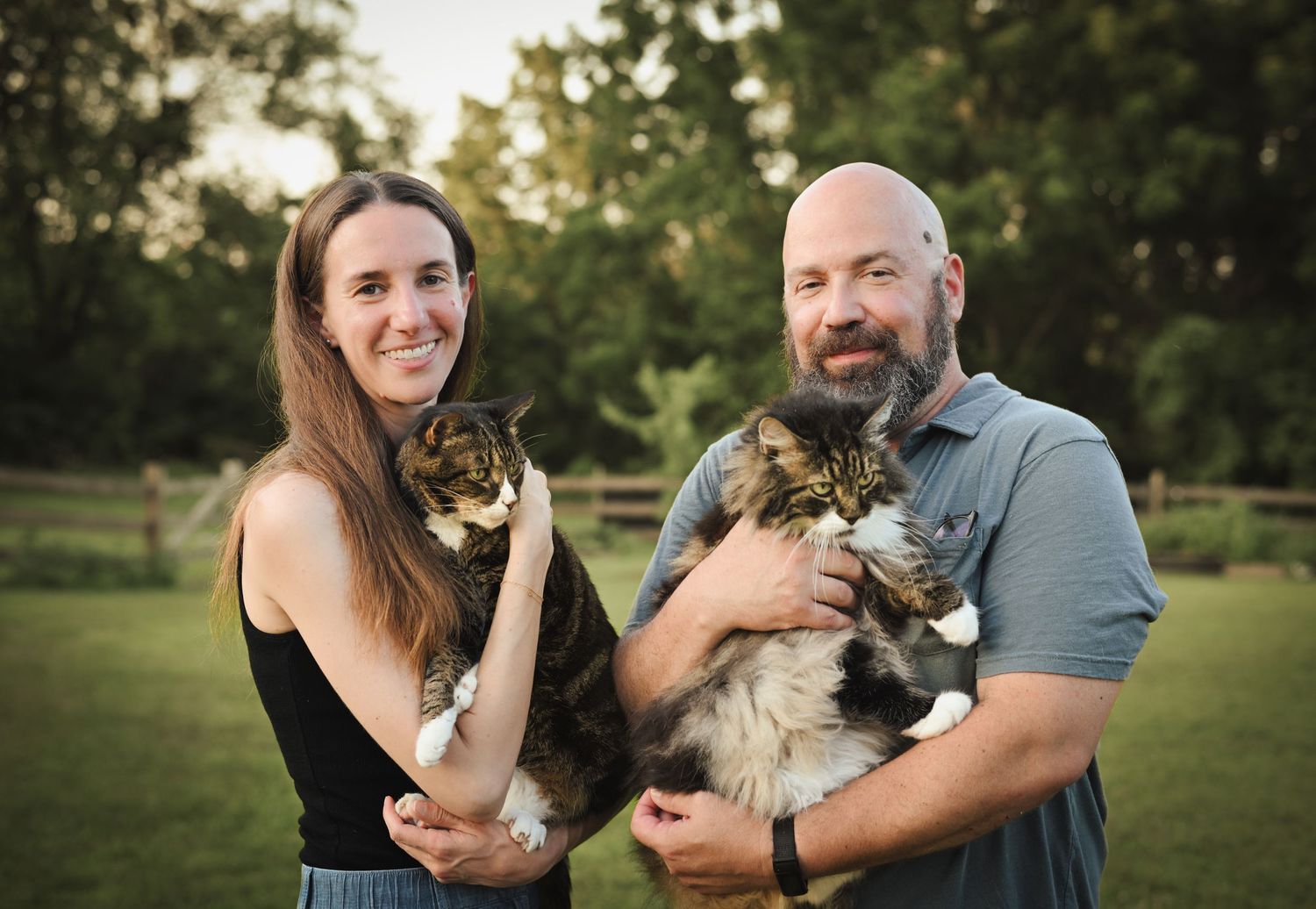 Couple holds their pet cat while sharing loving moments outdoors.