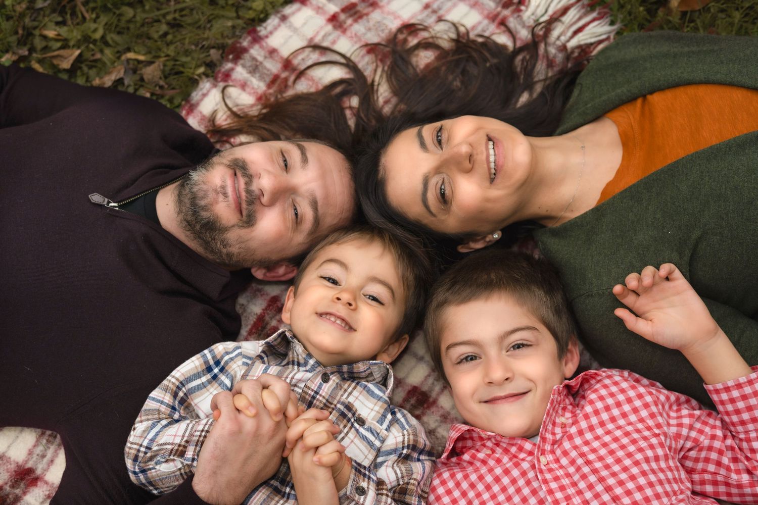 Family lying on blanket during cozy fall photo session outdoors.