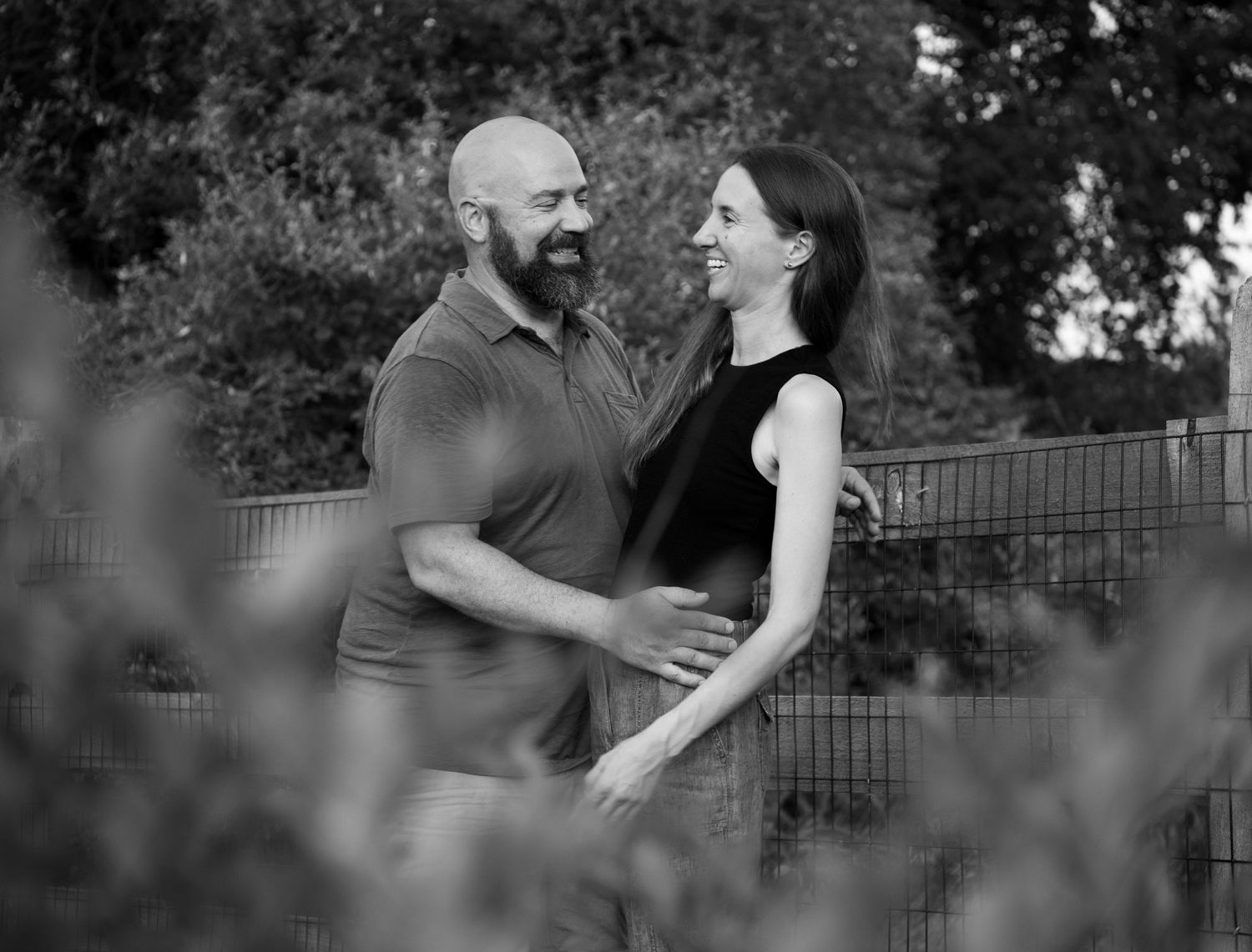 Black and white artistic portrait of a couple in a garden setting.