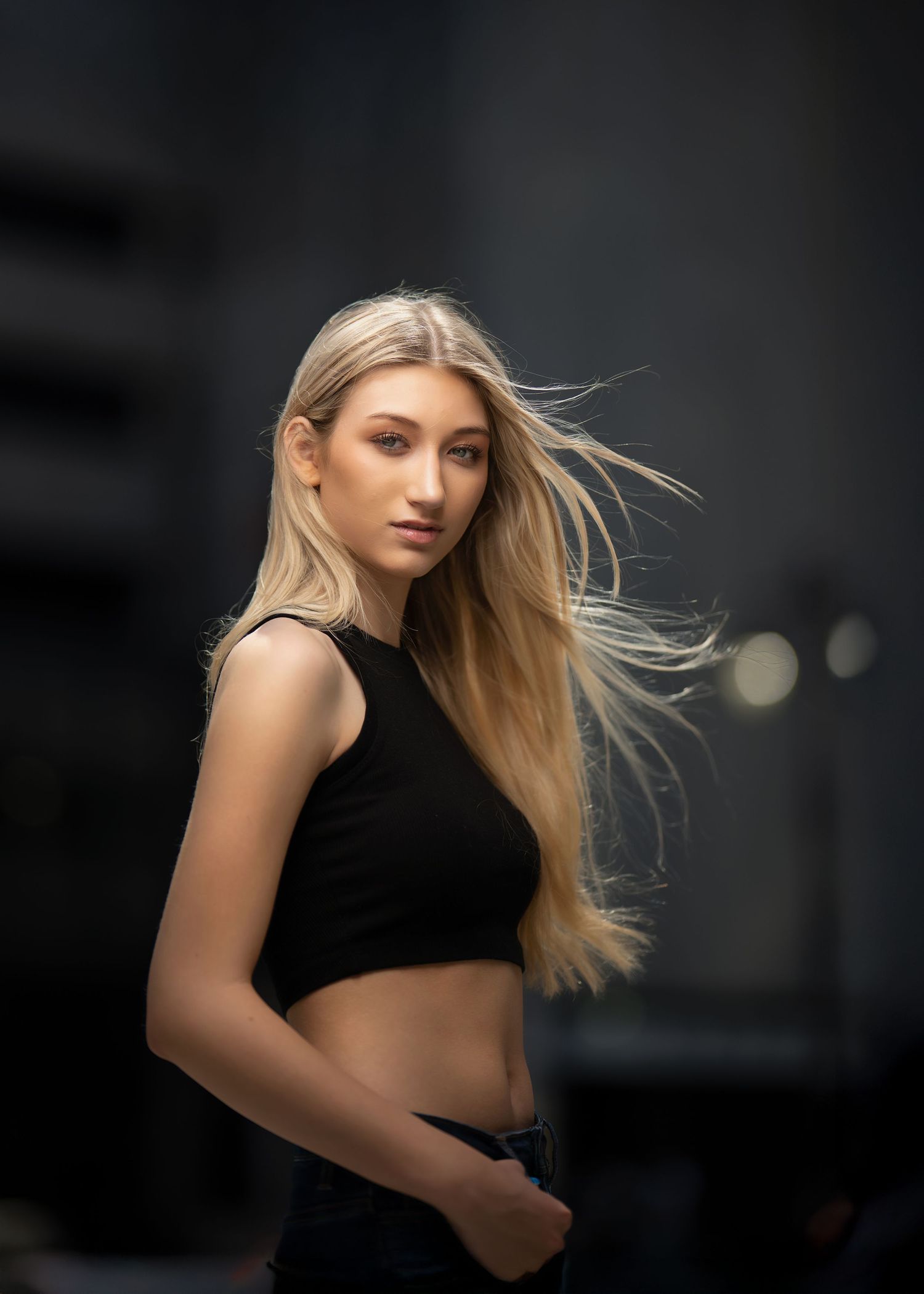 A high school senior posing outdoors with hair blowing in the wind during her glam portrait photo session on the Main Line, PA.