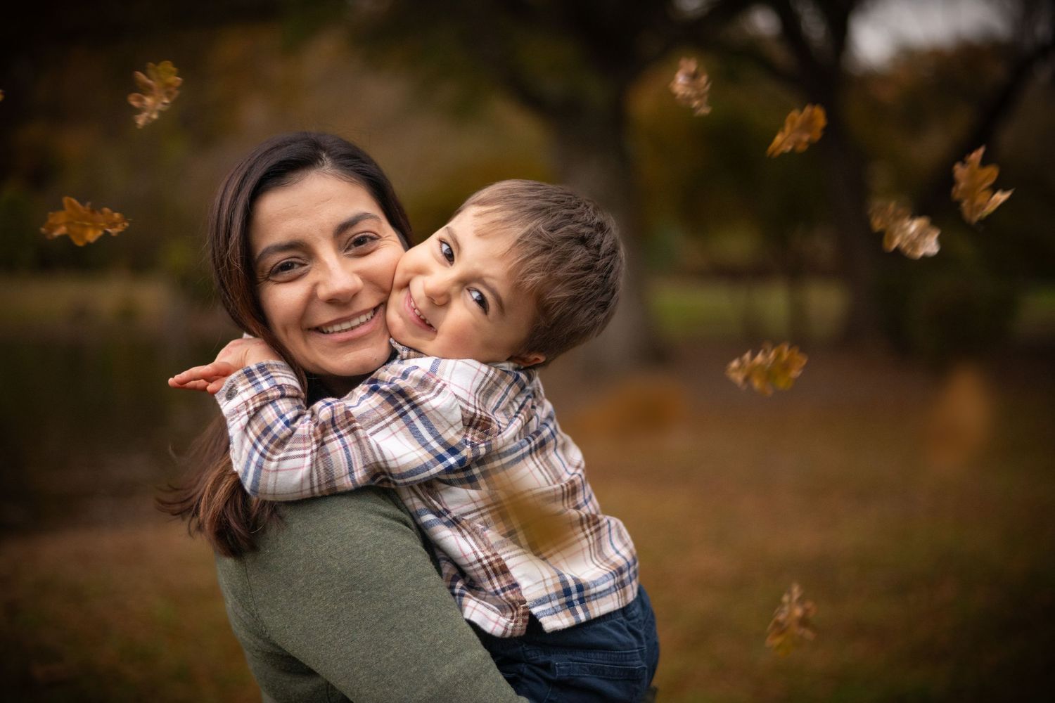 Autumn family photo session with falling leaves in warm golden light.