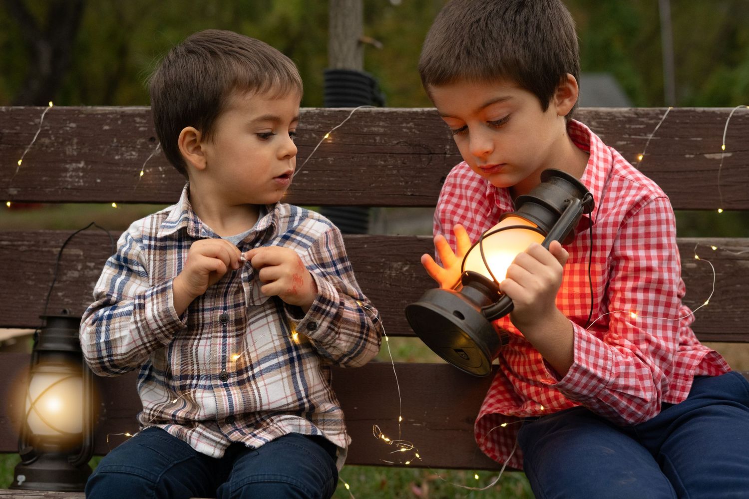 Children share playful moments on a wooden bench with a lantern in the background.