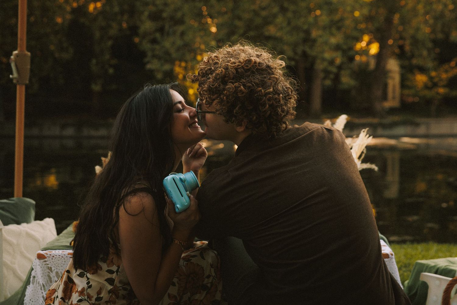 A romantic sunset picnic scene by the water with warm golden lighting.
