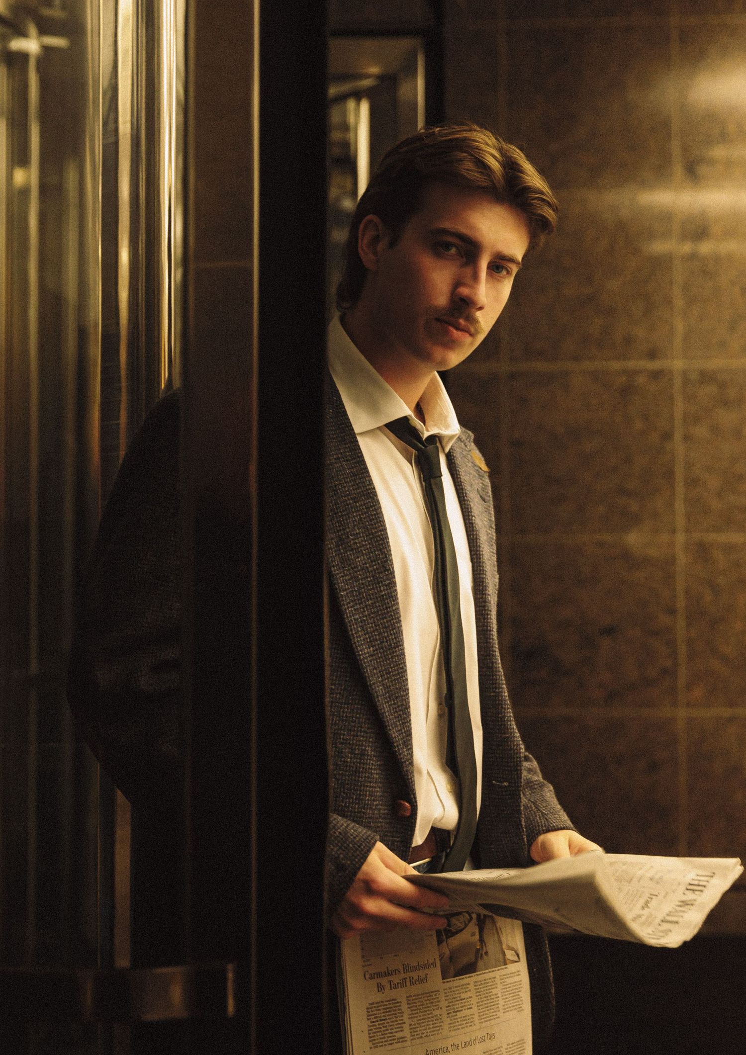Man in formal attire reads newspaper in dimly lit vintage hallway with dramatic lighting.