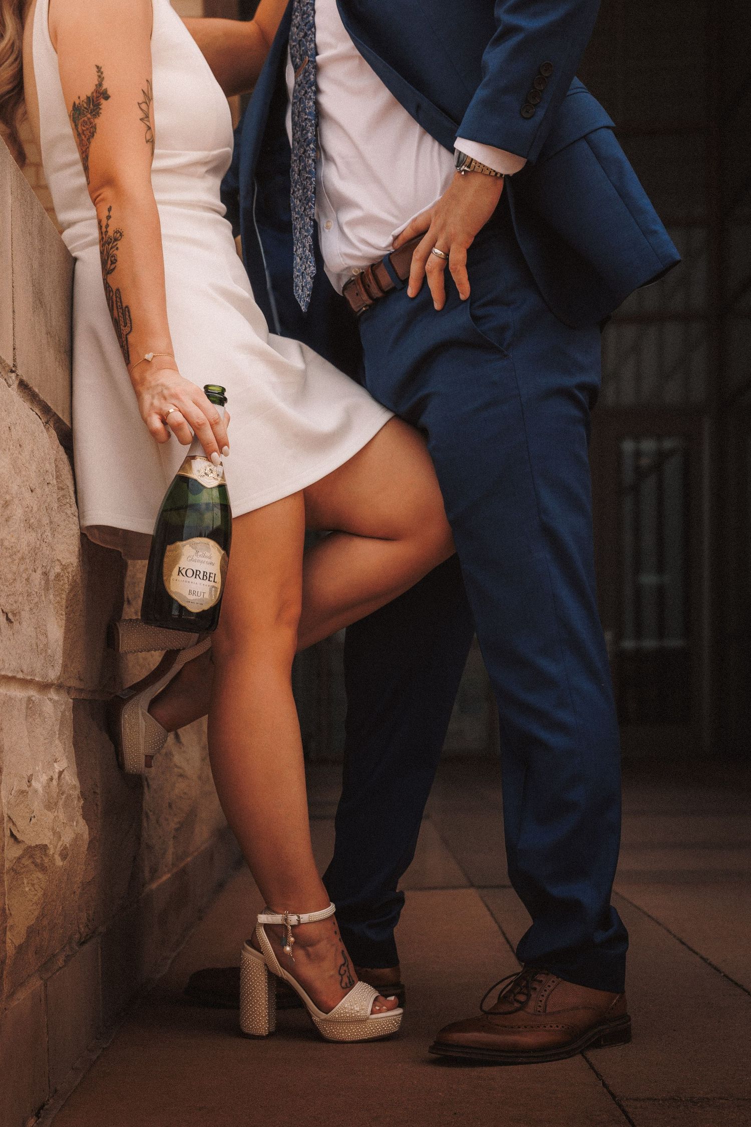 Close-up shots of legs showing a couple in formal wear with white heels and navy suit near stone columns.