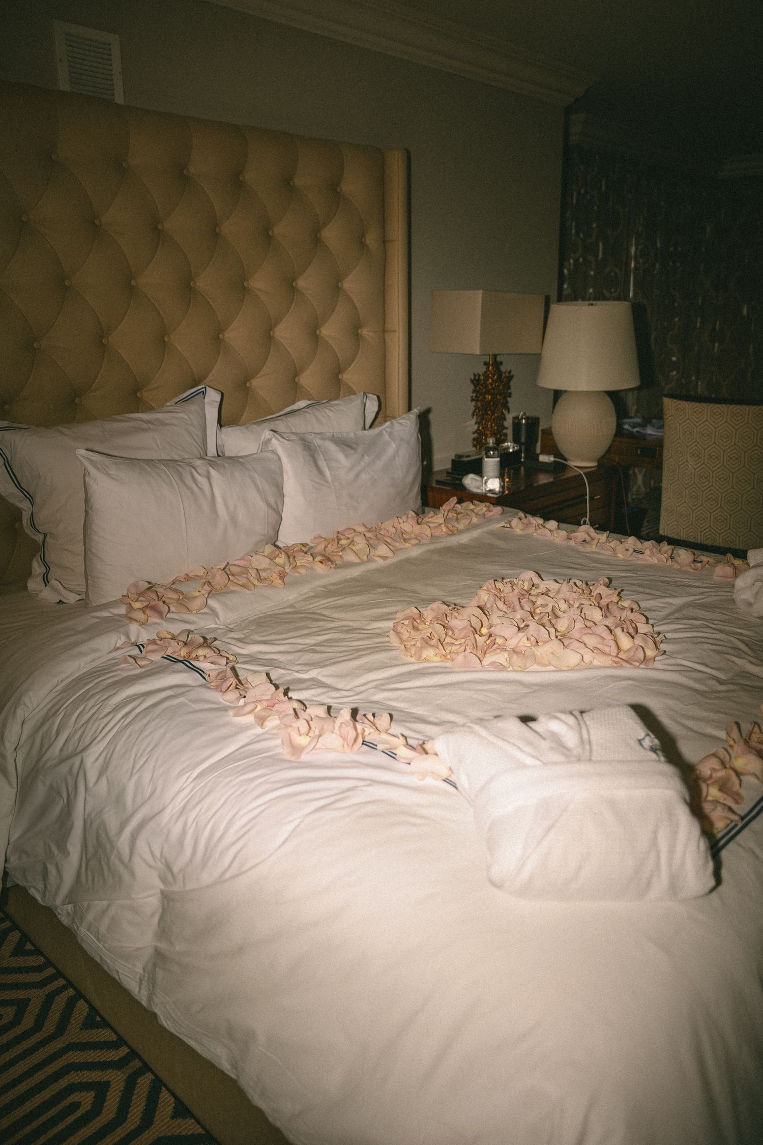 Hotel bridal suite bed decorated with pink rose petals and white towel swans.