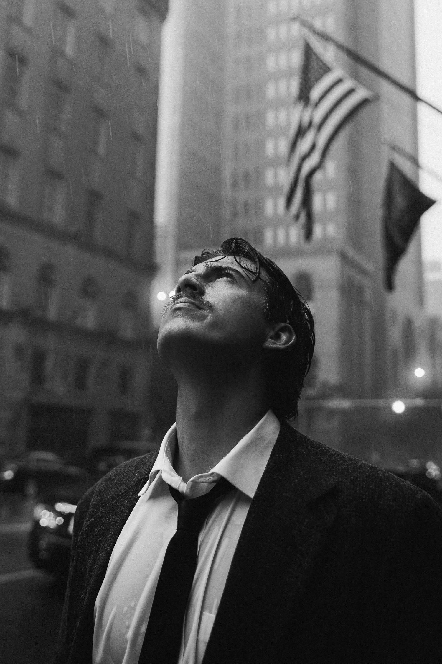 A monochrome sequence showing someone in a suit tilting their head back in an urban environment.