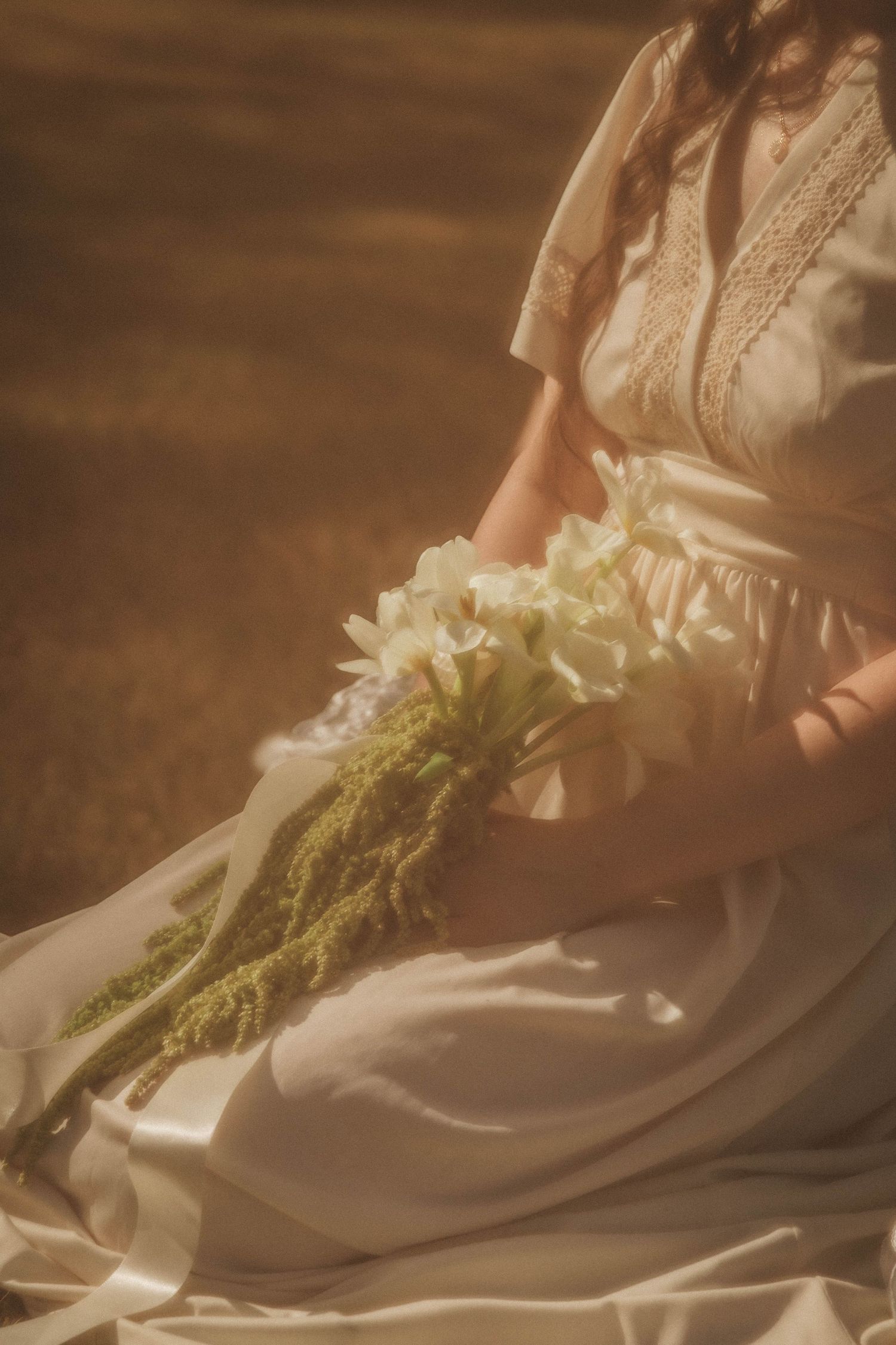 Delicate lace details and floral elements adorn the hem of an elegant white vintage-style dress.