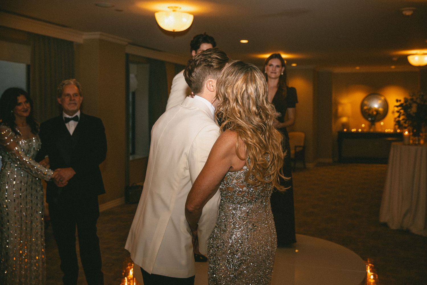Couple sharing a romantic dance at an elegant wedding reception in a warmly lit ballroom.