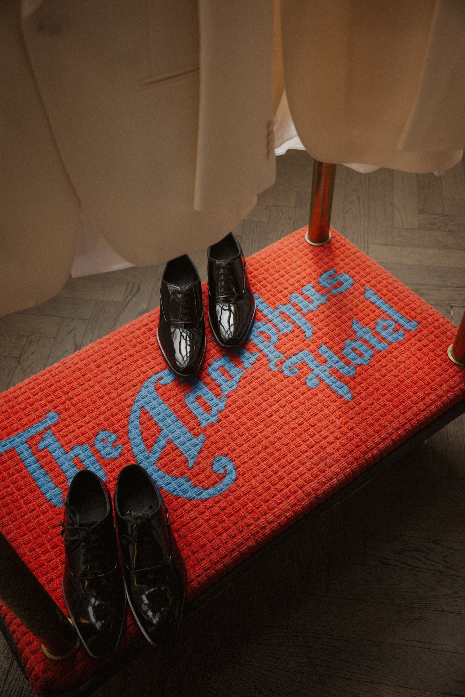 Black dress shoes displayed on a red hotel luggage rack with The Adolphus Hotel logo.