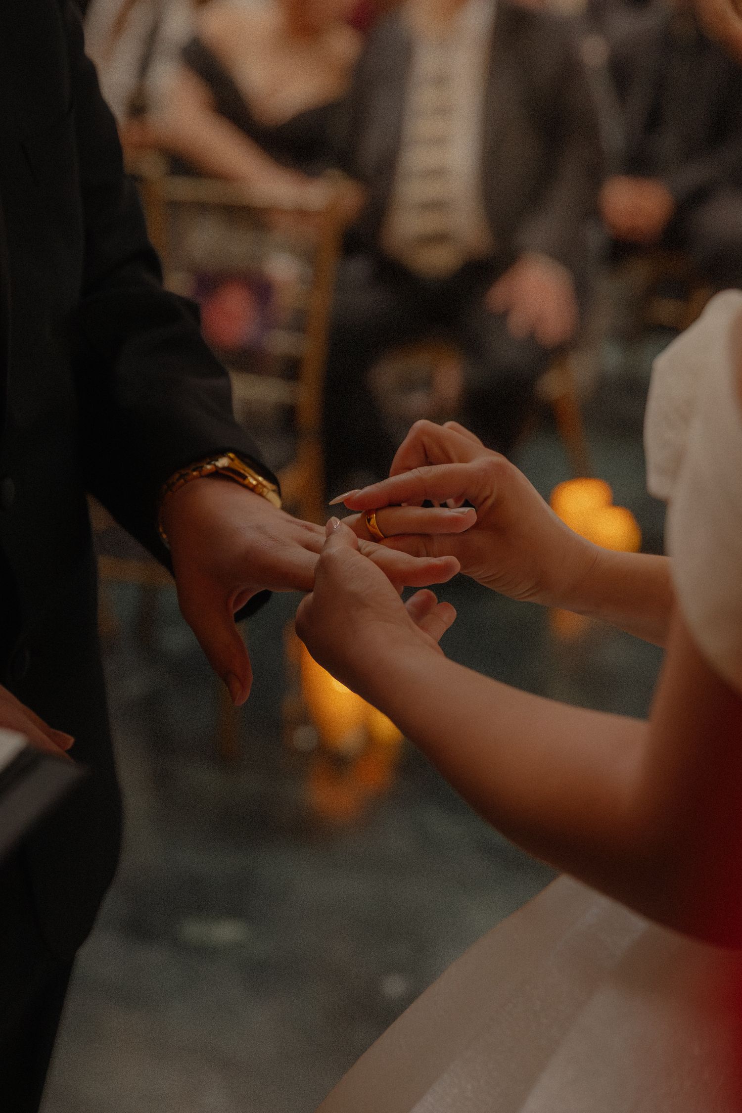 Close-up of bride placing wedding ring on grooms finger during ceremony exchange of vows.
