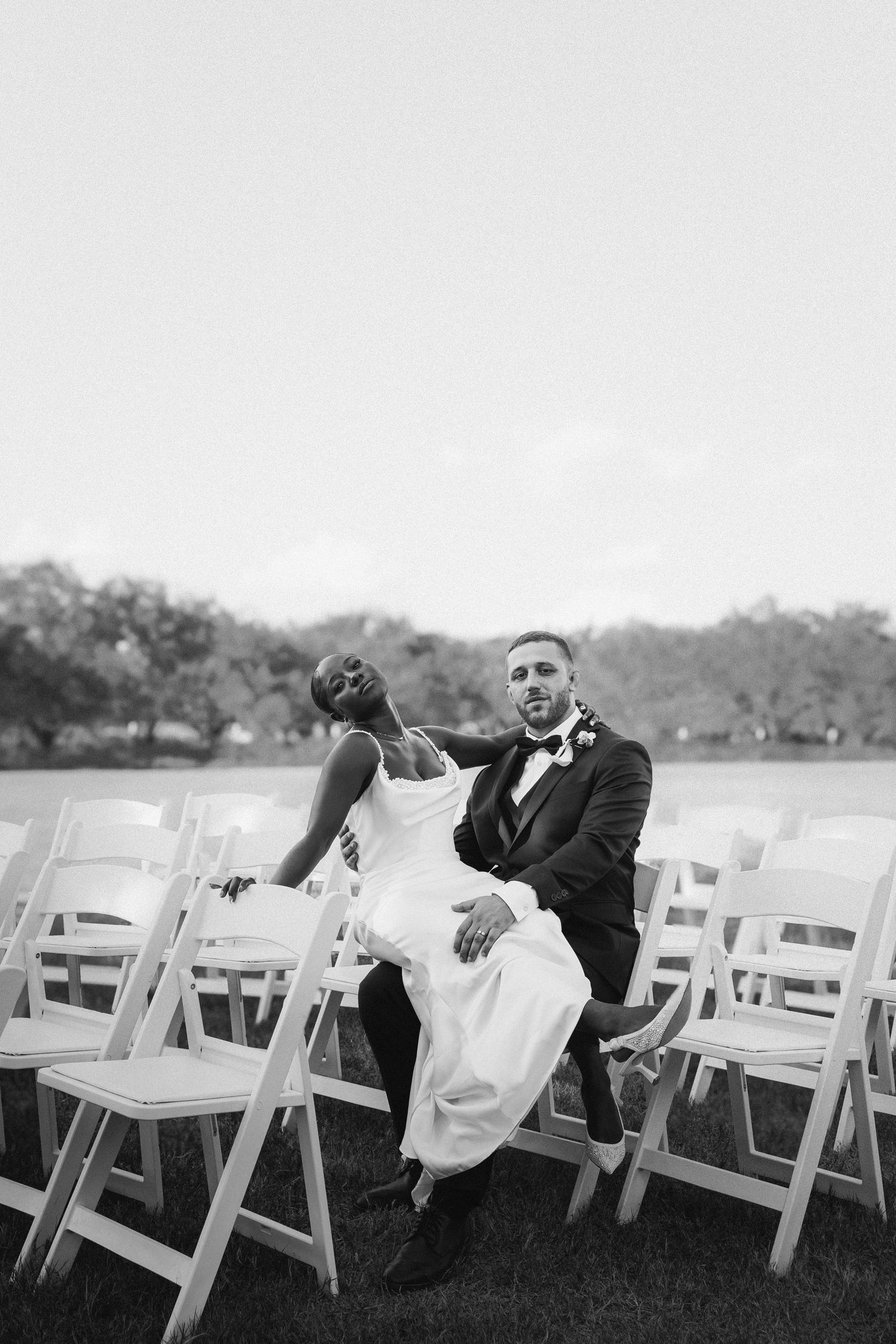 A romantic black and white photo sequence showing a couple playfully interacting among white folding chairs outdoors.