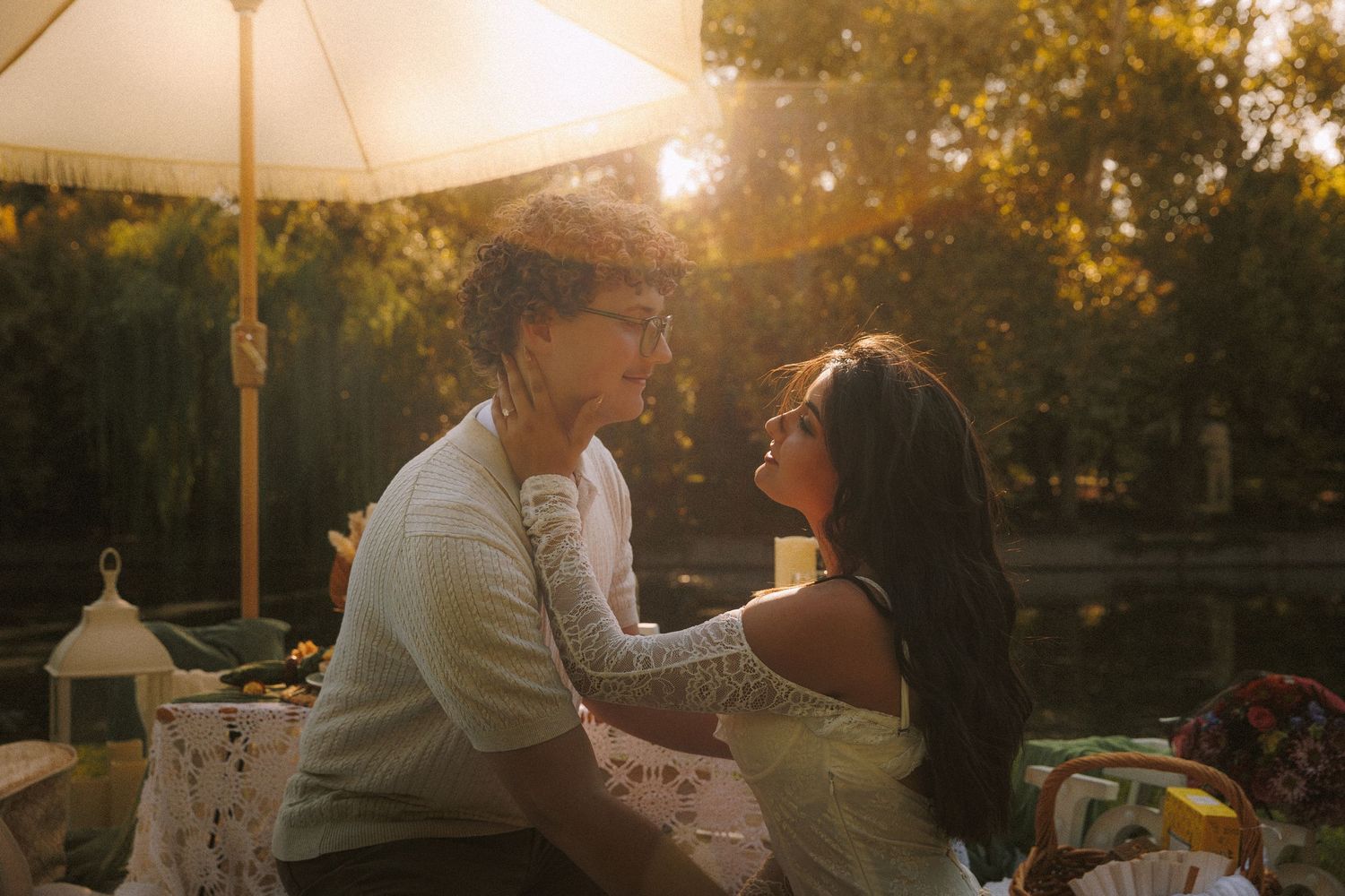 Couple sharing an intimate moment at an outdoor dinner party during golden hour sunset.