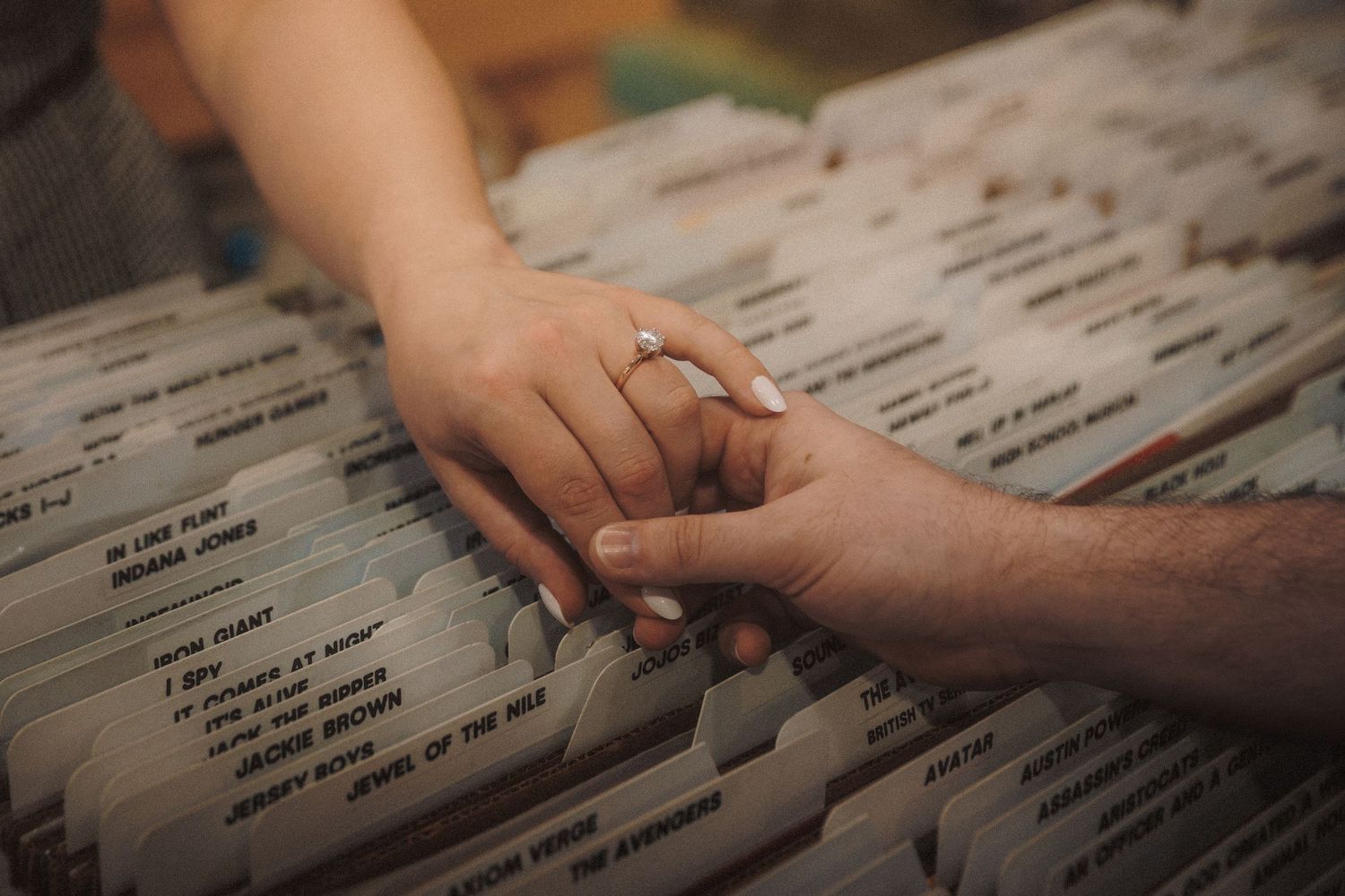 Hands sorting through alphabetically organized vinyl record collection in store display.