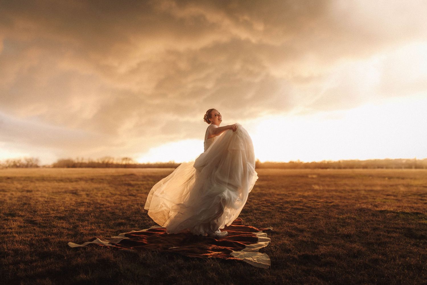 Person in flowing white dress runs across a dramatic sunset-lit field creating a ethereal silhouette effect.
