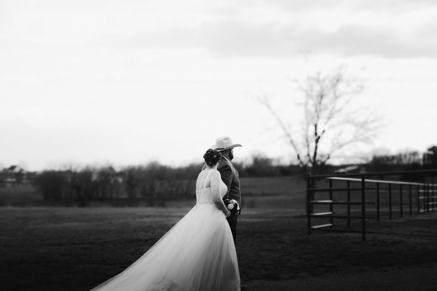 A black and white wedding photograph series showing romantic outdoor scenes with trees and fences in the background.