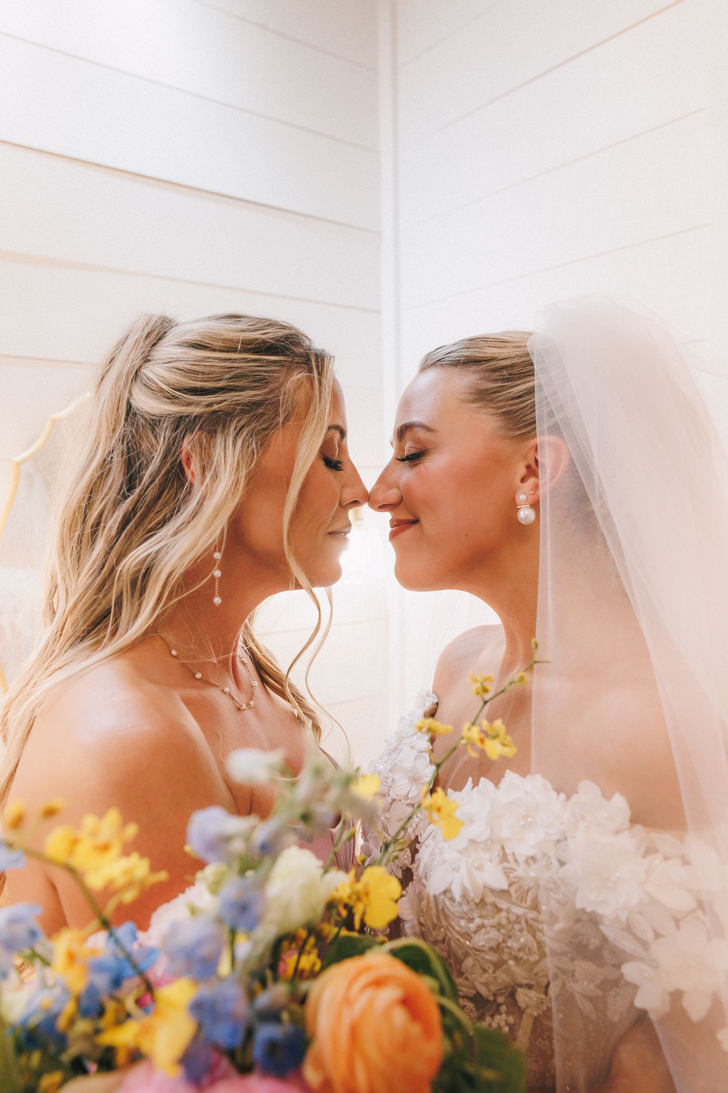 Close-up of bridal moment with colorful yellow and blue floral bouquet.