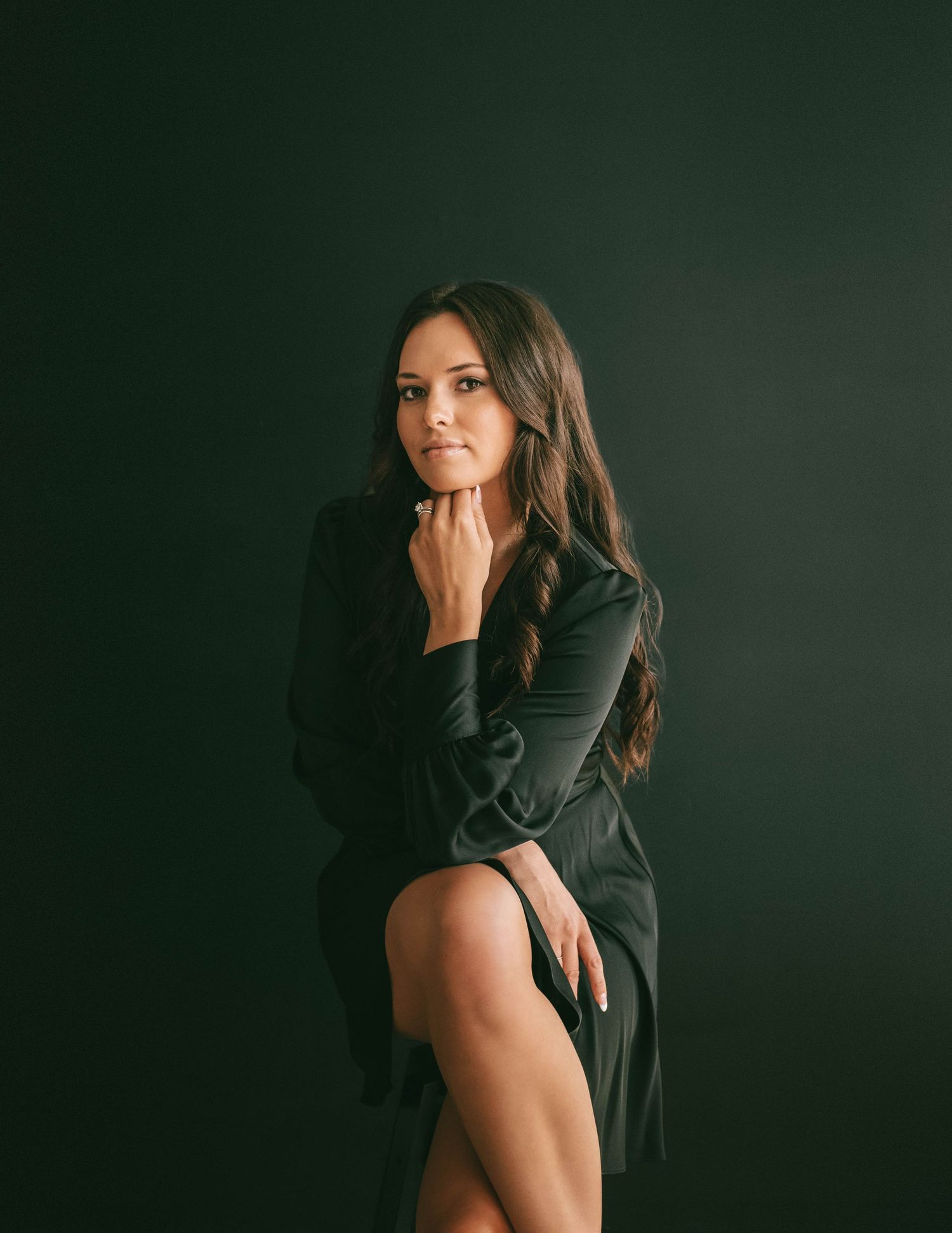 Artistic dark studio photoshoot featuring dramatic shadows and a black outfit against a deep green background.