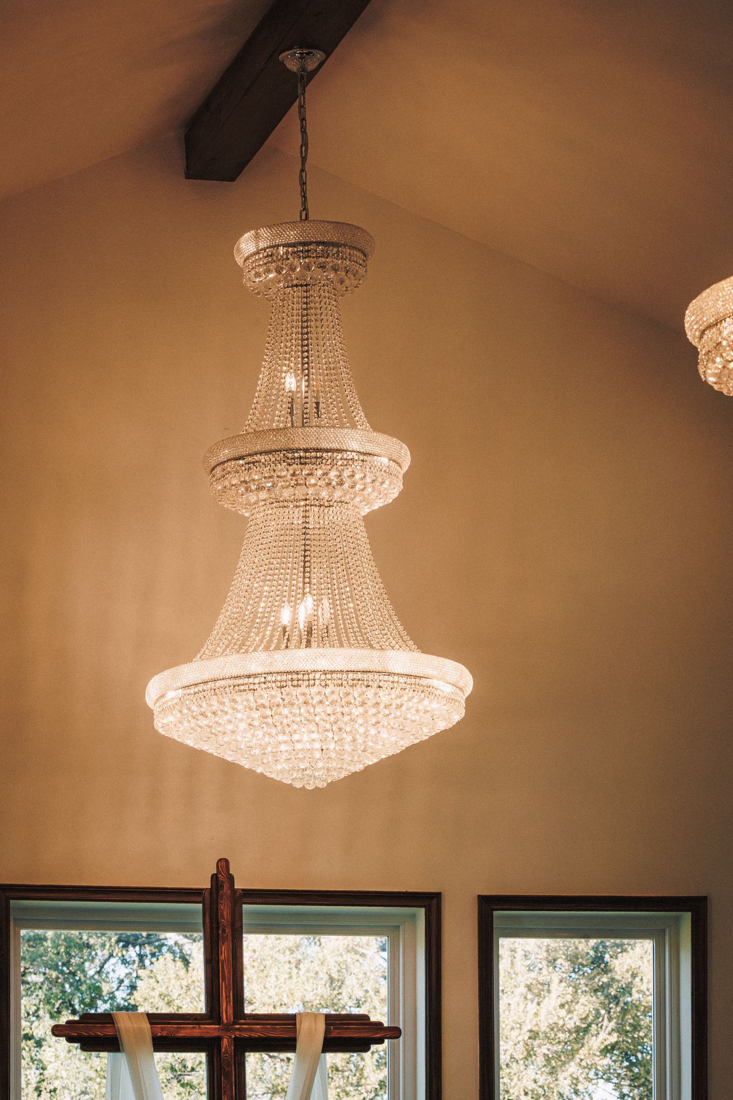 Grand crystal chandelier hanging above wooden cross in elegant wedding chapel interior.