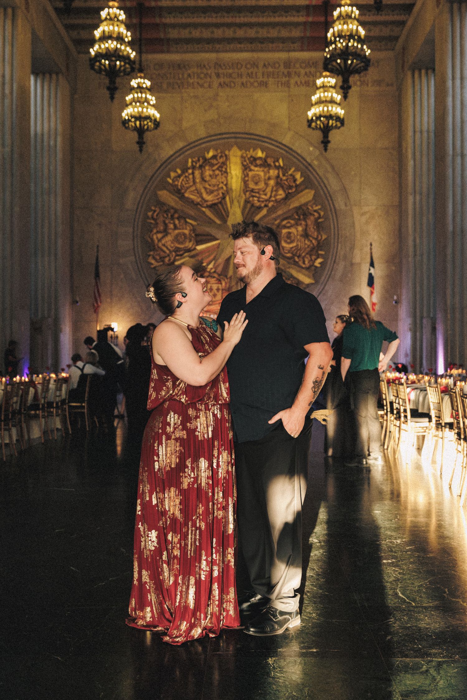 Couple shares romantic dance moment in grand ornate wedding reception hall with chandeliers.