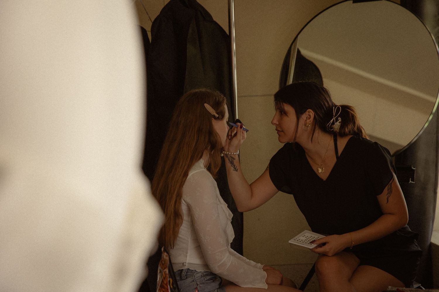 Makeup artist applying eyebrow makeup to bride before wedding ceremony.