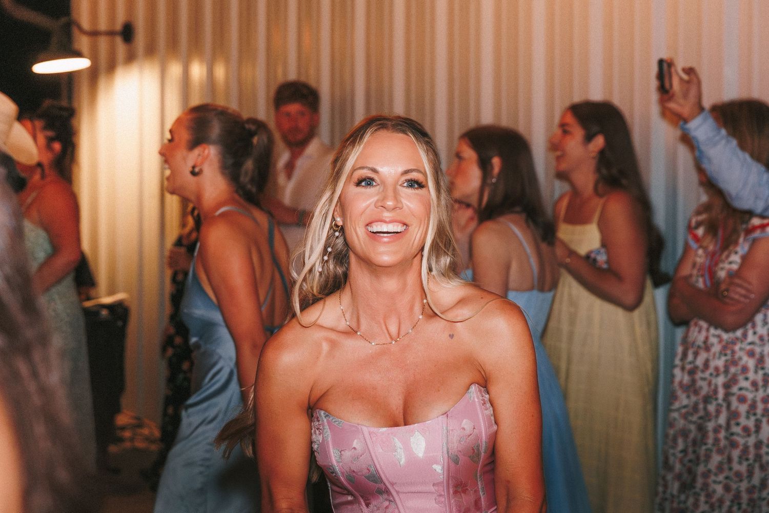 Wedding guests dancing and celebrating on a crowded dance floor at an indoor reception.