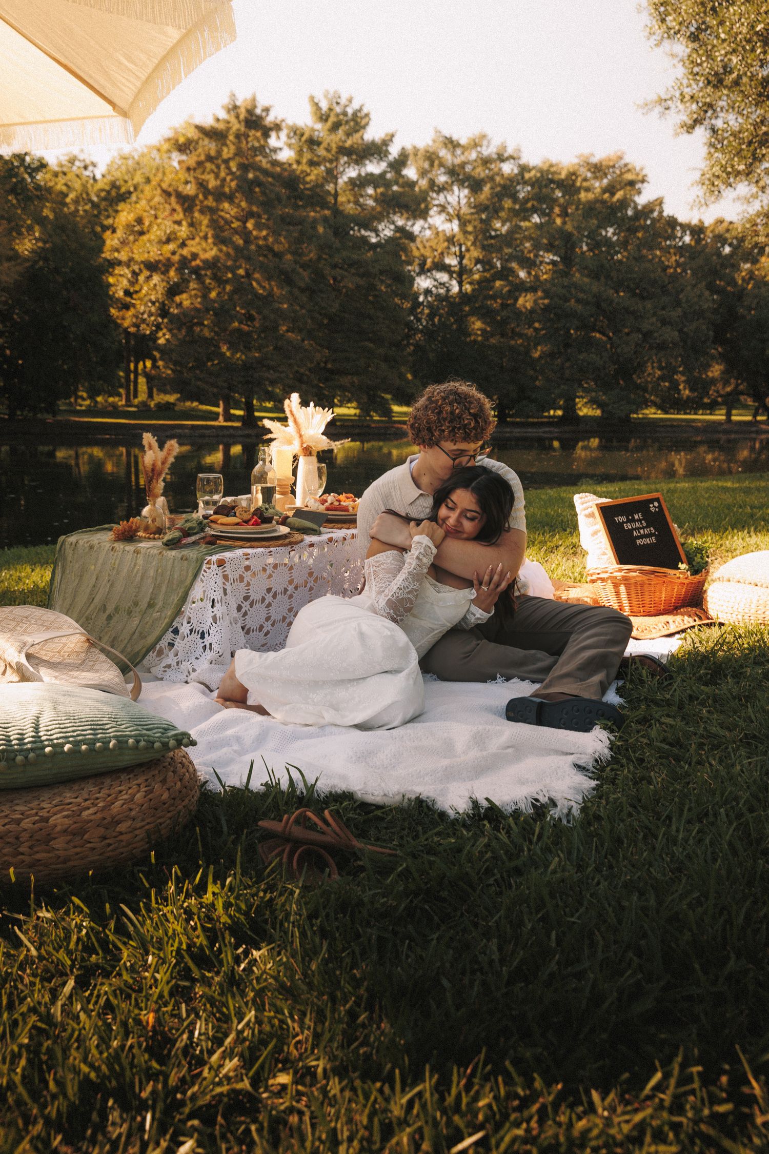 Cozy outdoor picnic setup with plush cushions and blankets on grass at sunset.