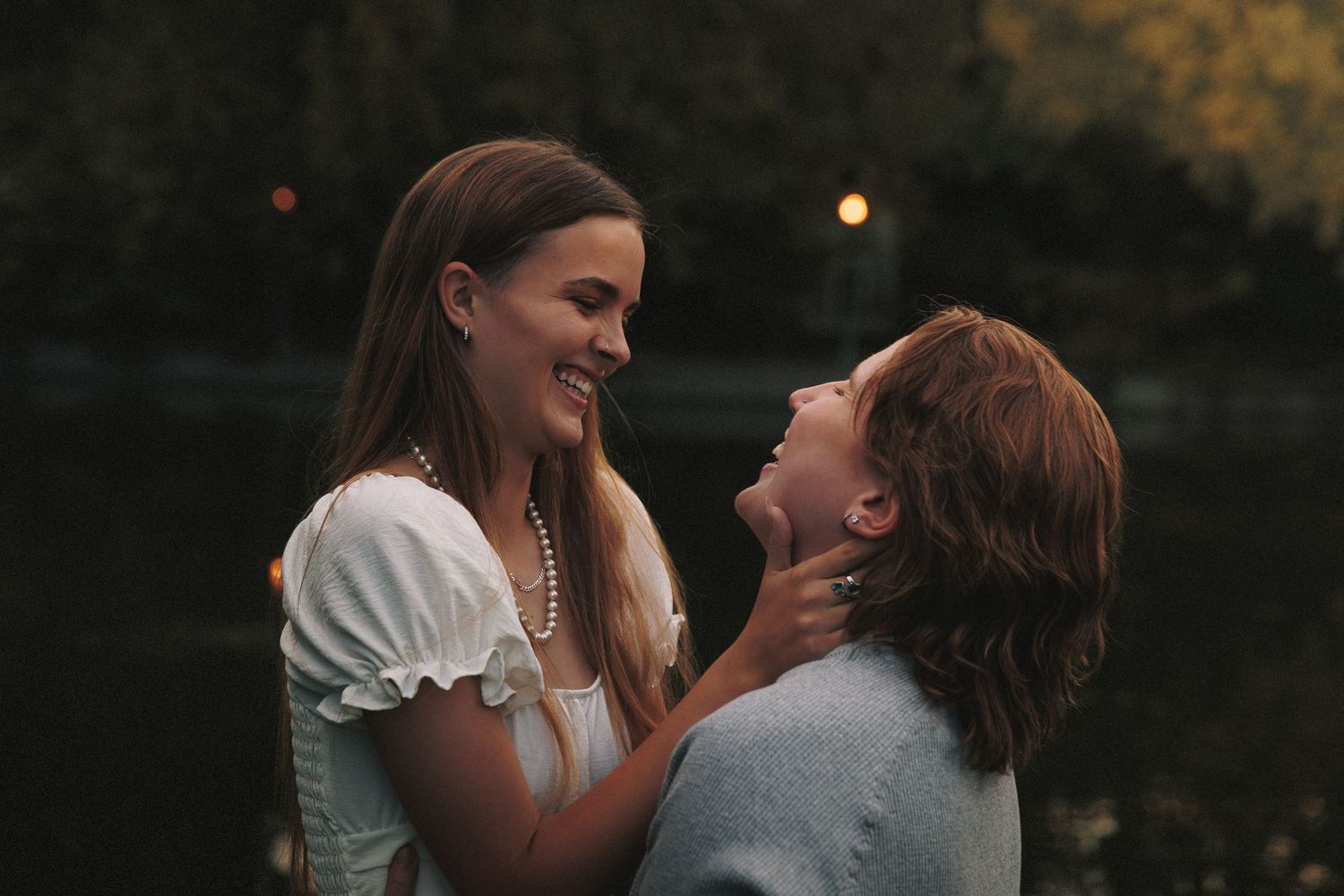 A couple shares an intimate moment together while embracing in a romantic outdoor setting at dusk.