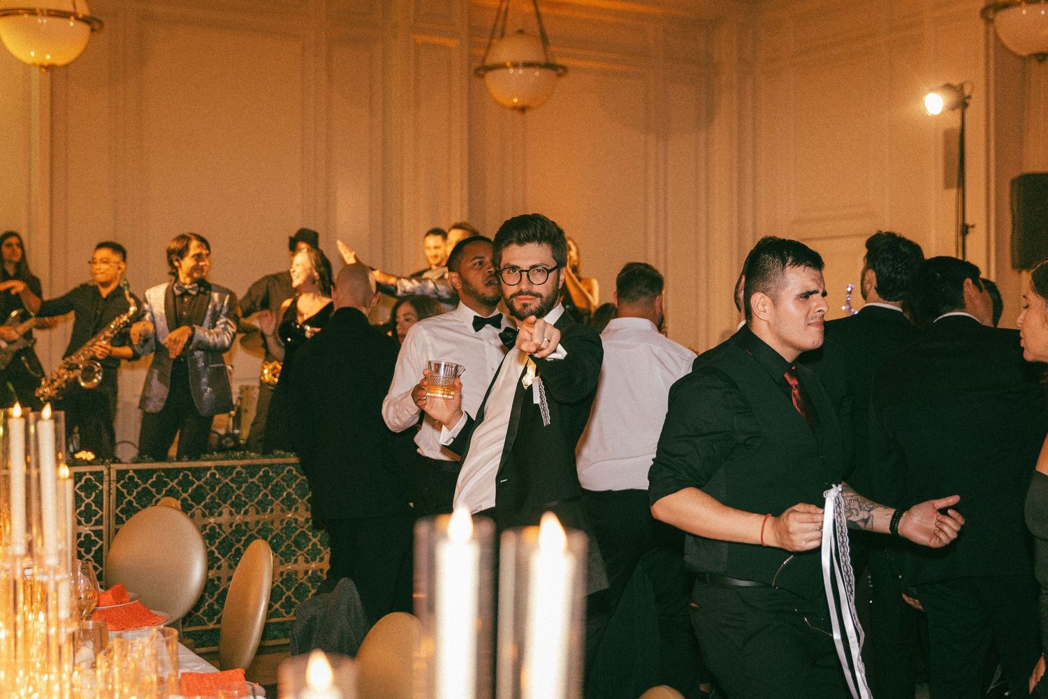 Wedding guests dance and celebrate as a live band performs at an elegant reception.