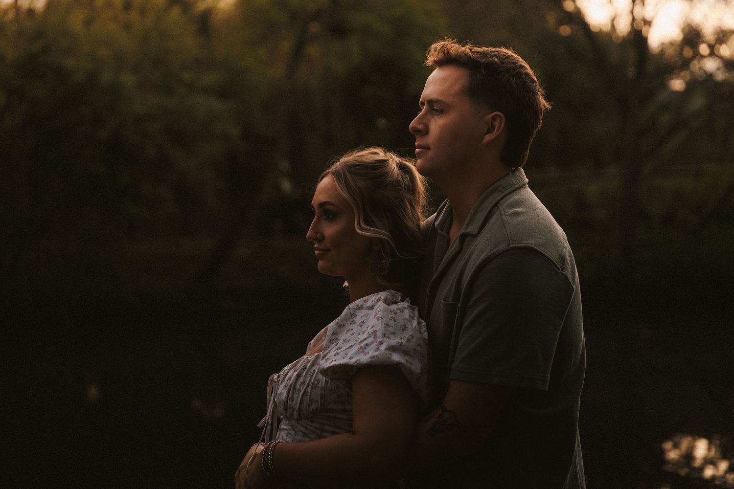 Couple standing close together gazing into the distance during a warm golden sunset.