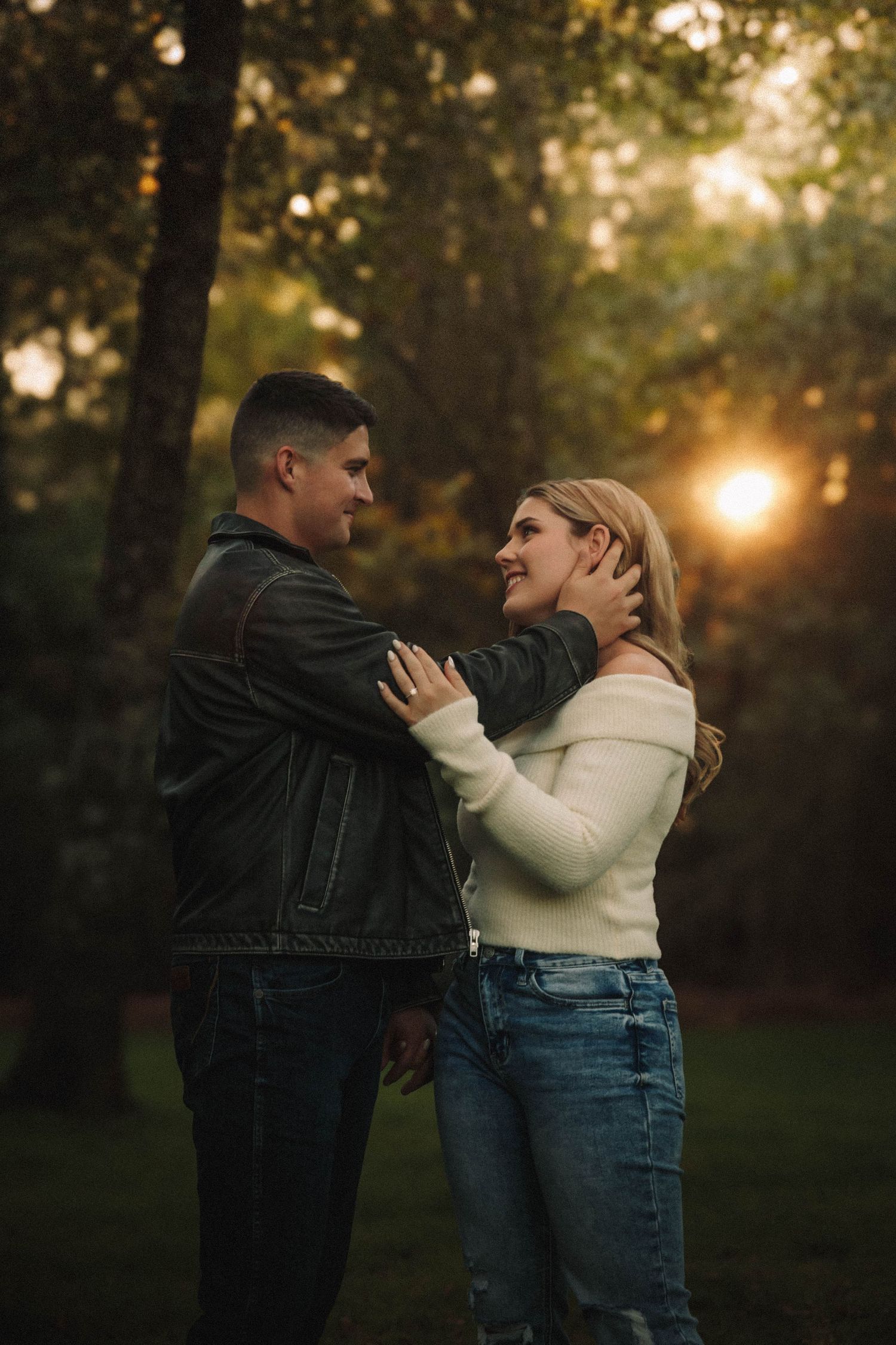 A romantic couple embraces in a forest during golden hour sunset creating a intimate silhouette.