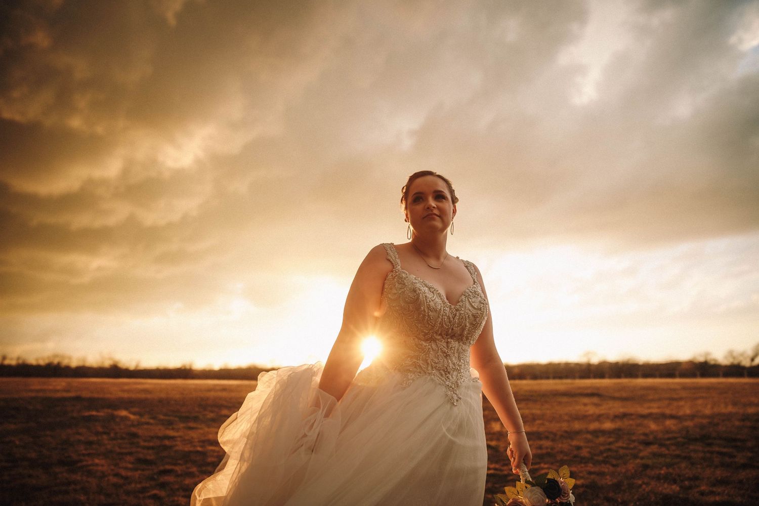 Dramatic sunset silhouettes across a rural field with ethereal golden light filtering through white fabric.
